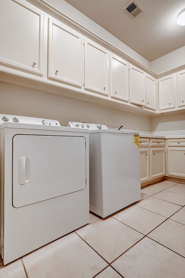 laundry room with cabinets, separate washer and dryer, and light tile patterned flooring