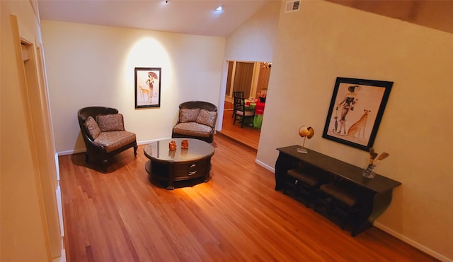 sitting room with hardwood / wood-style flooring and lofted ceiling