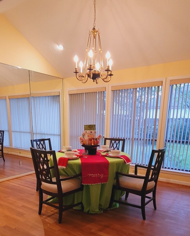 dining space featuring wood-type flooring, high vaulted ceiling, and a notable chandelier