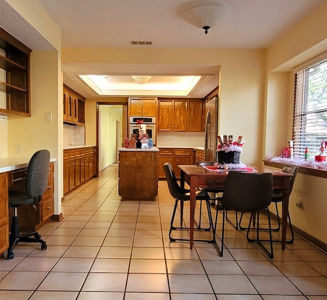 tiled dining area with a raised ceiling