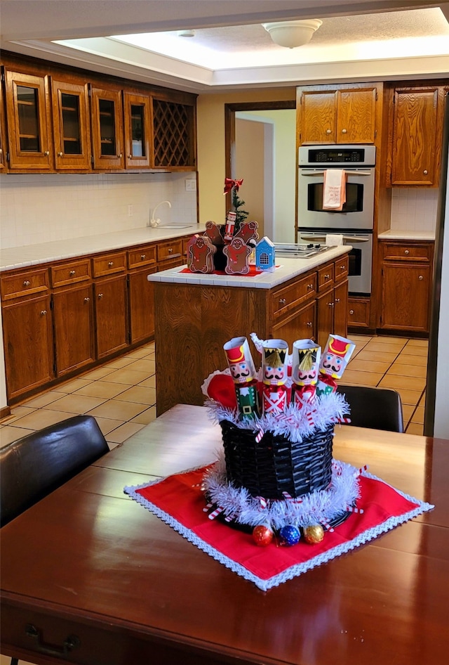 kitchen with a center island, sink, light tile patterned flooring, and stainless steel double oven