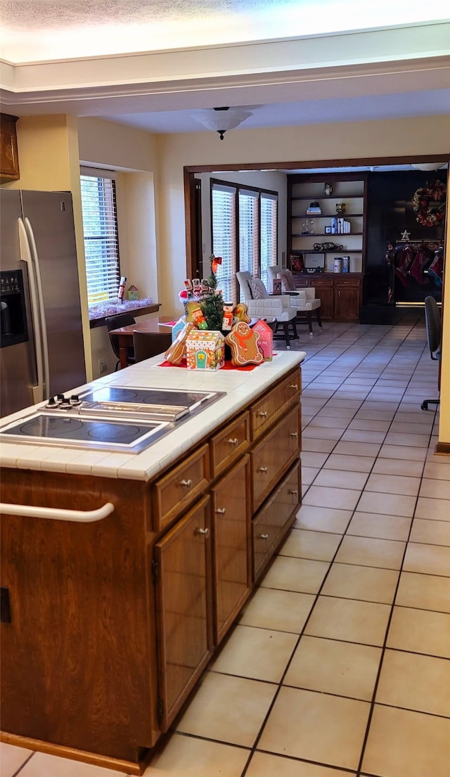 kitchen featuring a wealth of natural light, stainless steel fridge, light tile patterned floors, and a textured ceiling