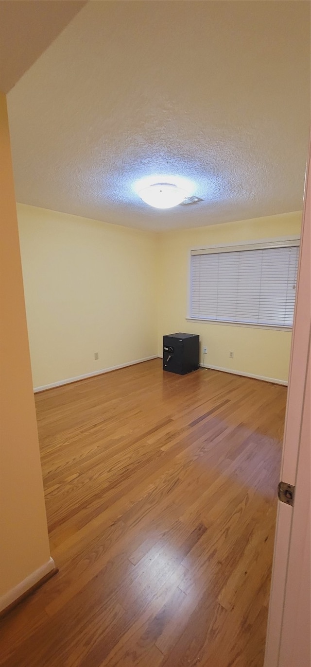 empty room featuring wood-type flooring and a textured ceiling