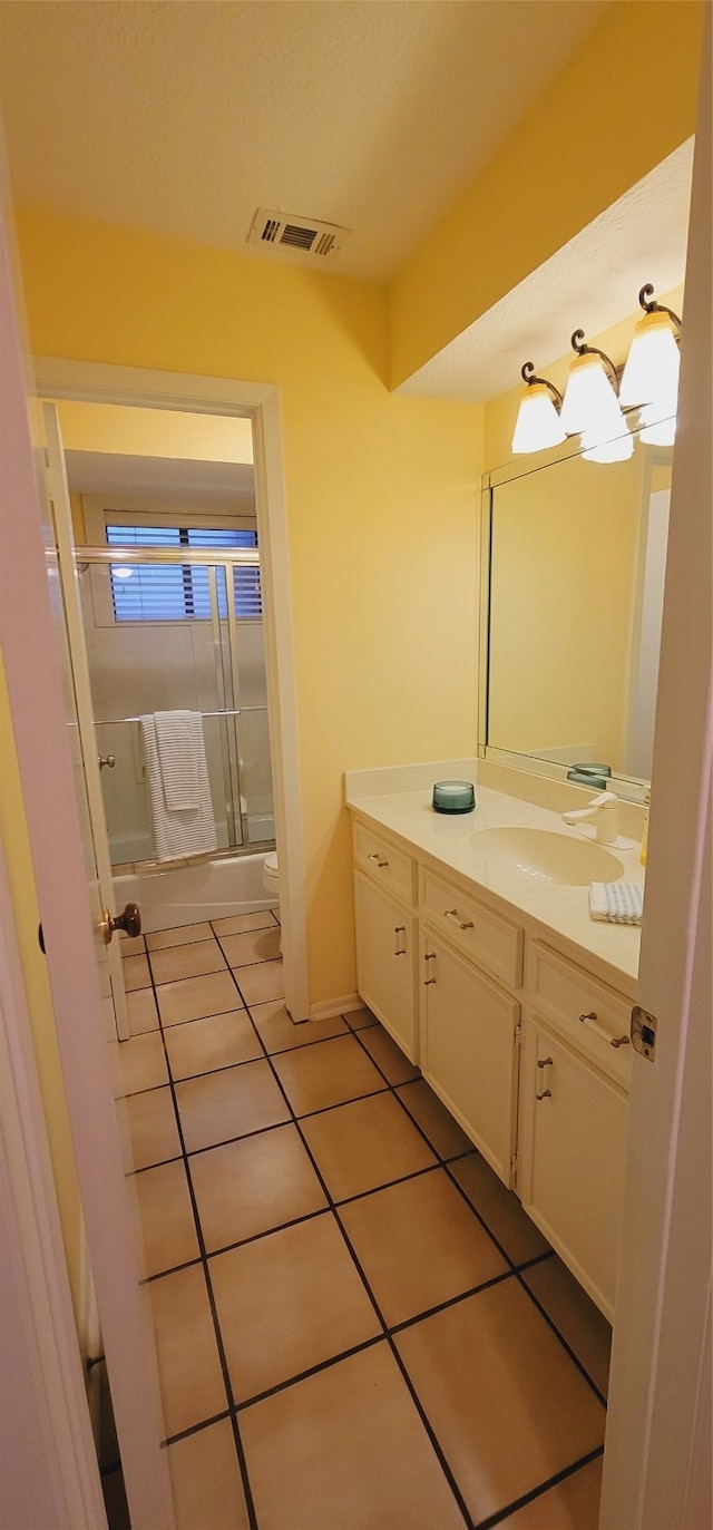 full bathroom featuring tile patterned flooring, vanity, bath / shower combo with glass door, and toilet