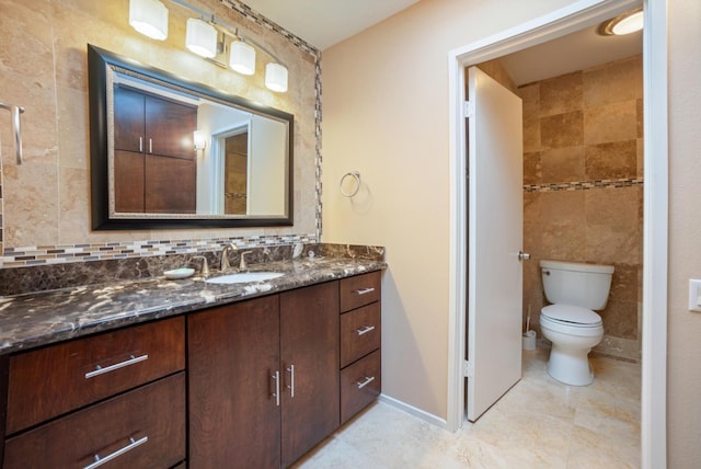 bathroom featuring vanity, toilet, and tile walls