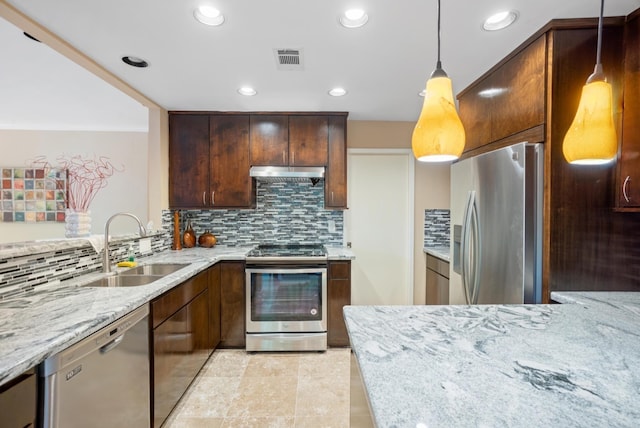 kitchen featuring sink, appliances with stainless steel finishes, tasteful backsplash, decorative light fixtures, and light stone counters