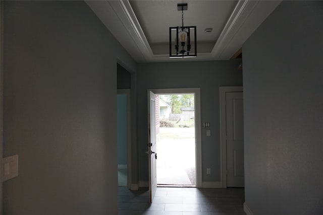 doorway to outside featuring a notable chandelier and a raised ceiling