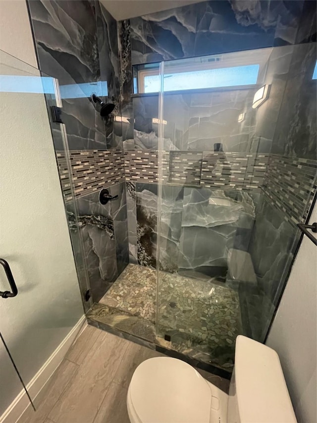 bathroom featuring toilet, hardwood / wood-style floors, and a shower with shower door