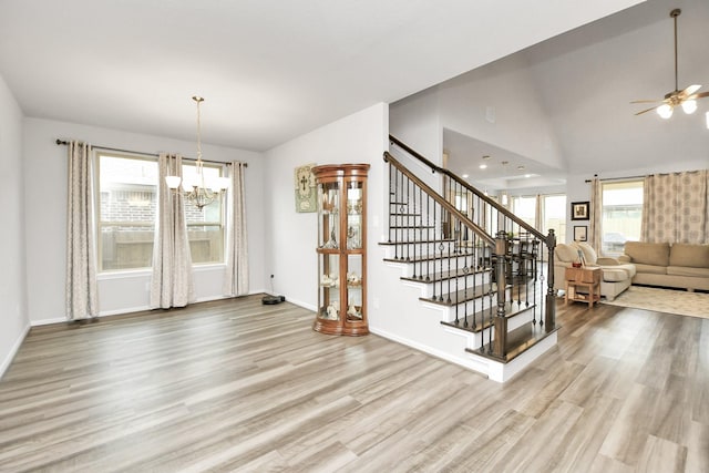 dining space featuring light hardwood / wood-style flooring, high vaulted ceiling, and ceiling fan with notable chandelier