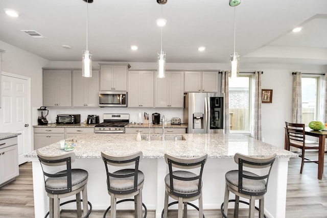 kitchen featuring appliances with stainless steel finishes, hanging light fixtures, a large island, and sink