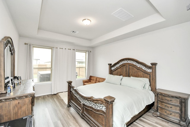 bedroom featuring a raised ceiling and light hardwood / wood-style flooring