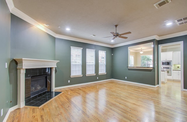 unfurnished living room featuring light hardwood / wood-style floors, ornamental molding, and a tile fireplace