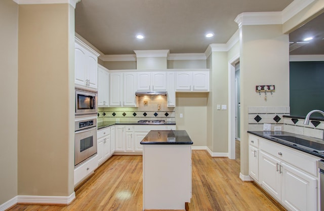 kitchen featuring stainless steel appliances, sink, light hardwood / wood-style flooring, a center island, and white cabinetry