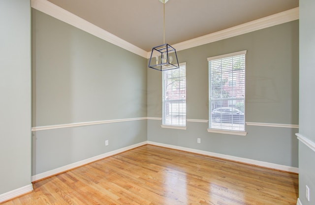 unfurnished room featuring hardwood / wood-style flooring, a notable chandelier, and crown molding