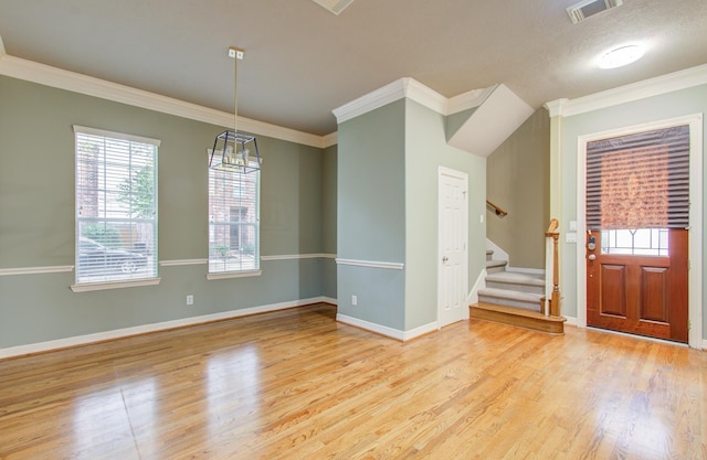 foyer with a healthy amount of sunlight, light hardwood / wood-style floors, and ornamental molding