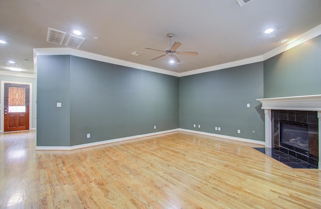 unfurnished living room with light hardwood / wood-style floors, ornamental molding, and a tile fireplace