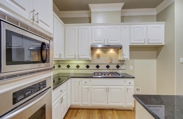 kitchen with white cabinets, light hardwood / wood-style floors, appliances with stainless steel finishes, and dark stone counters