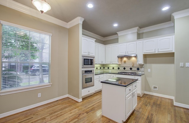 kitchen with stainless steel appliances, white cabinetry, light hardwood / wood-style floors, and crown molding