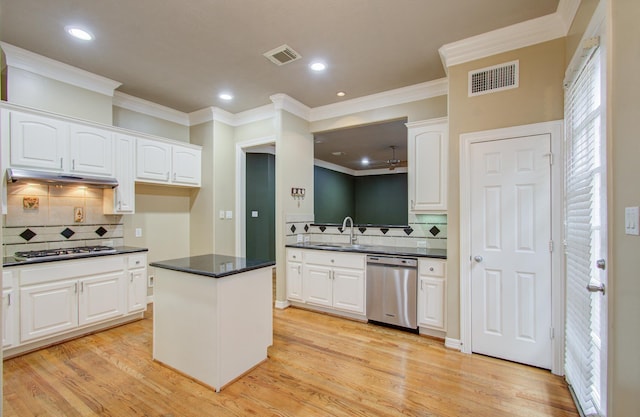 kitchen with appliances with stainless steel finishes, sink, white cabinets, light hardwood / wood-style floors, and a kitchen island