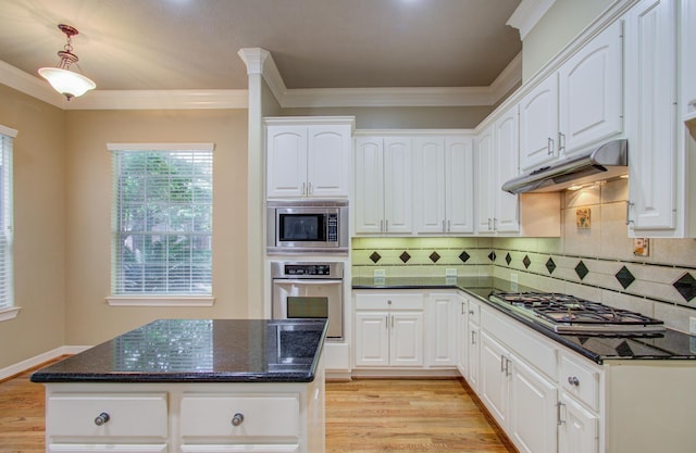 kitchen with crown molding, dark stone countertops, appliances with stainless steel finishes, light hardwood / wood-style floors, and white cabinetry