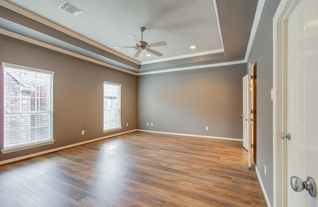 unfurnished room featuring a tray ceiling, a wealth of natural light, ceiling fan, and light wood-type flooring