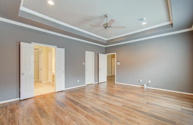 unfurnished bedroom featuring a tray ceiling, ceiling fan, and light hardwood / wood-style flooring