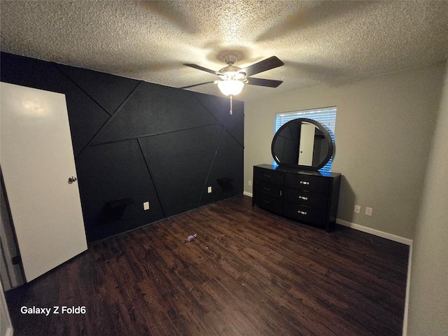 unfurnished bedroom with ceiling fan, dark wood-type flooring, and a textured ceiling