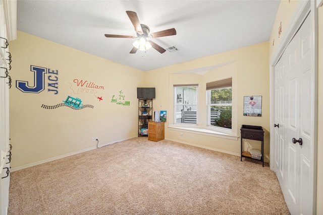 unfurnished bedroom with a textured ceiling, ceiling fan, light carpet, and a closet