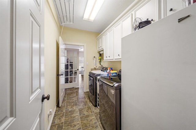 clothes washing area with washer and dryer and cabinets