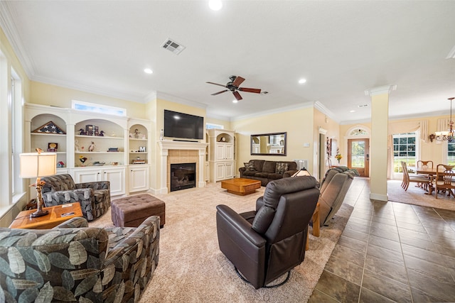 living room featuring tile patterned flooring, ceiling fan with notable chandelier, ornamental molding, and a tile fireplace