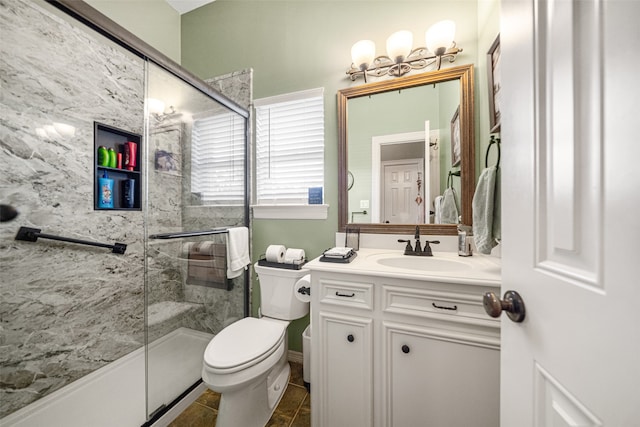 bathroom with tile patterned floors, a shower with door, vanity, and toilet