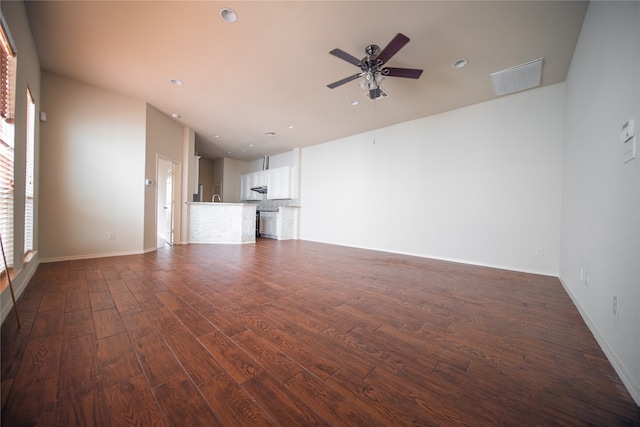 unfurnished living room featuring ceiling fan and dark wood-type flooring