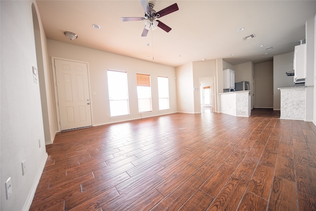 unfurnished living room featuring ceiling fan and dark wood-type flooring