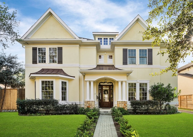 view of front of home with stucco siding, a standing seam roof, fence, a front yard, and metal roof