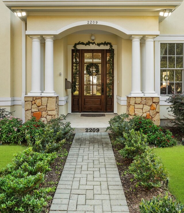 doorway to property with stone siding and stucco siding