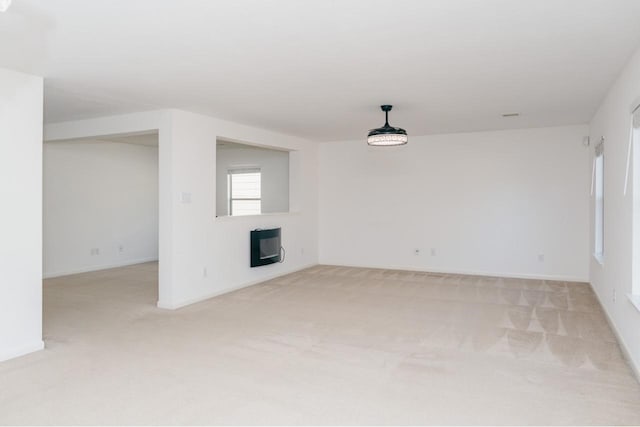 unfurnished living room featuring heating unit and light carpet