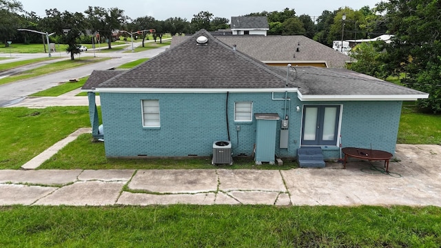 rear view of property with french doors, central air condition unit, a patio area, and a lawn