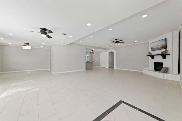 unfurnished living room with ceiling fan, light tile patterned floors, a fireplace, and ornamental molding