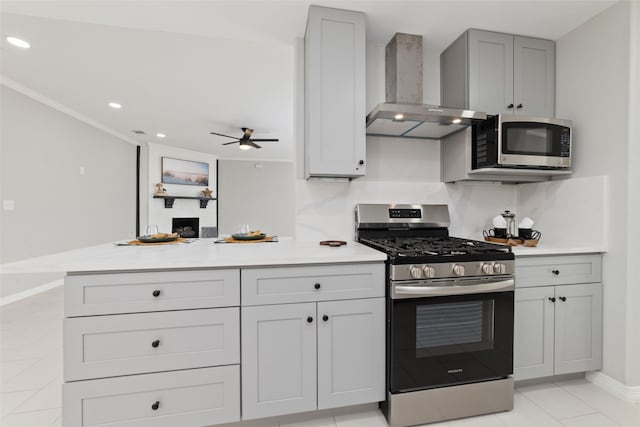 kitchen with stainless steel appliances, ceiling fan, wall chimney range hood, gray cabinets, and light tile patterned flooring