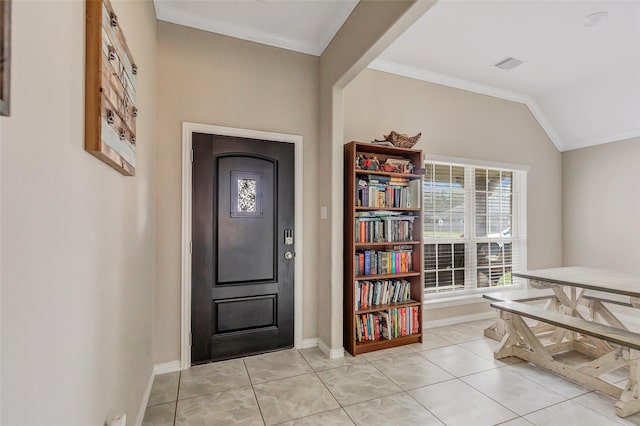 entrance foyer with light tile patterned flooring, vaulted ceiling, and ornamental molding