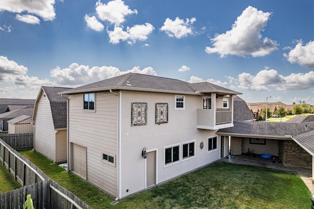 back of house featuring a lawn, a balcony, and a garage