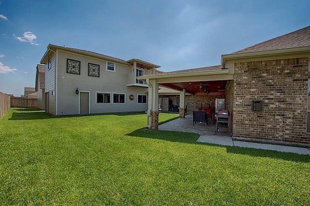 rear view of property with a lawn, ceiling fan, and a patio