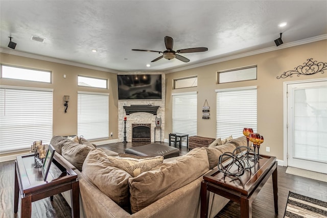 living room with hardwood / wood-style flooring, a stone fireplace, plenty of natural light, and crown molding