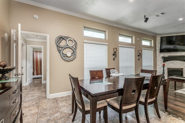 dining space featuring a stone fireplace, a healthy amount of sunlight, and ornamental molding