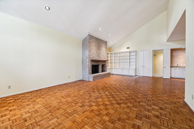 unfurnished living room with parquet floors, a fireplace, high vaulted ceiling, and built in shelves