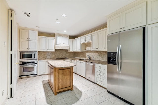 kitchen featuring backsplash, stainless steel appliances, sink, a center island, and light tile patterned flooring