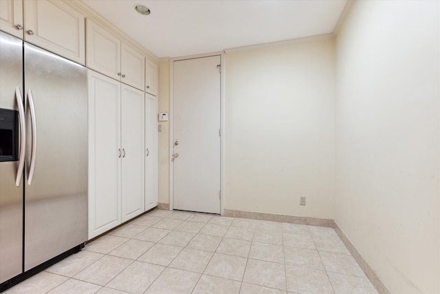 interior space with stainless steel refrigerator with ice dispenser, light tile patterned floors, and ornamental molding