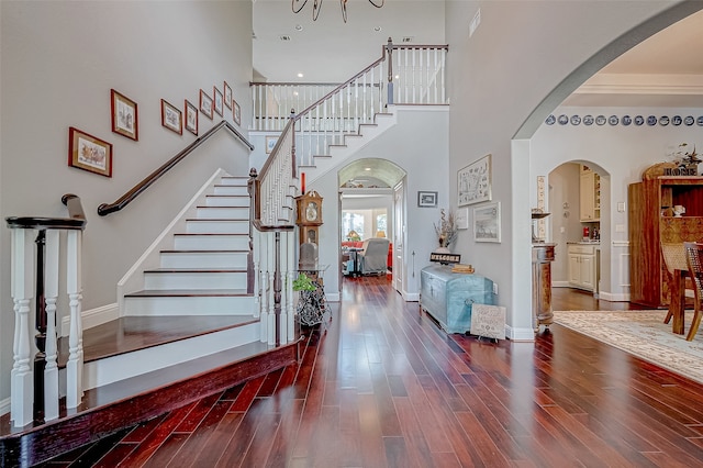 entrance foyer featuring a high ceiling, crown molding, and dark wood-type flooring