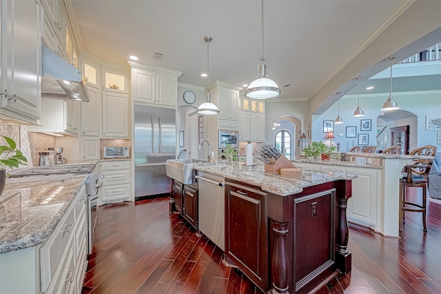 kitchen with sink, a spacious island, decorative light fixtures, and premium appliances