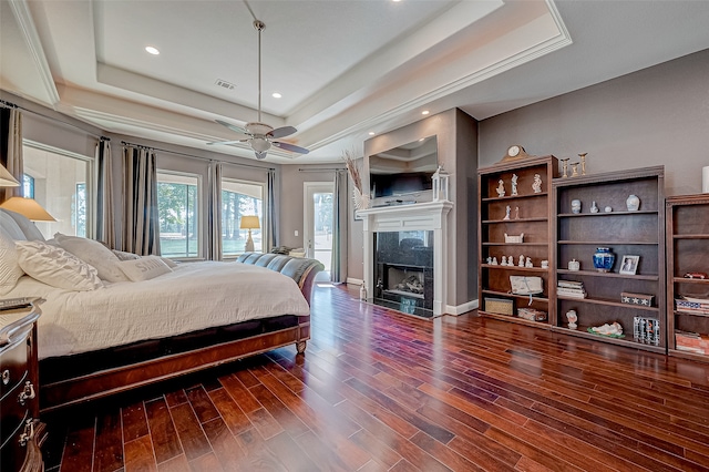 bedroom featuring access to exterior, dark hardwood / wood-style floors, a raised ceiling, and ceiling fan